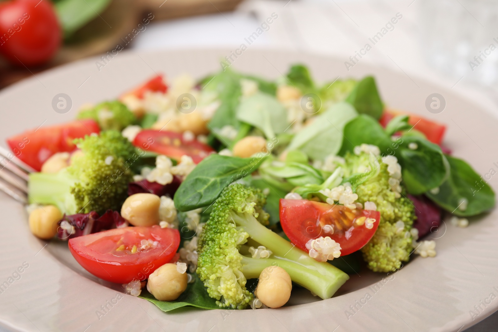 Photo of Healthy meal. Tasty salad with quinoa, chickpeas and vegetables in plate, closeup