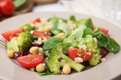 Photo of Healthy meal. Tasty salad with quinoa, chickpeas and vegetables in plate, closeup