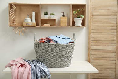 Wicker basket with dirty laundry on white table in bathroom