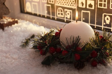 Photo of Beautiful burning candle with Christmas decor near window, space for text