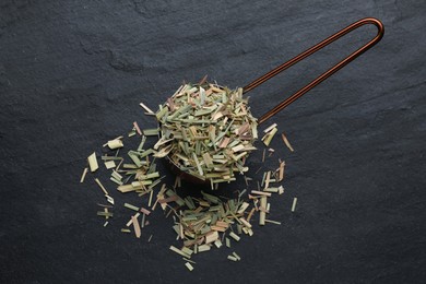 Photo of Small saucepan with aromatic dried lemongrass on black table, flat lay