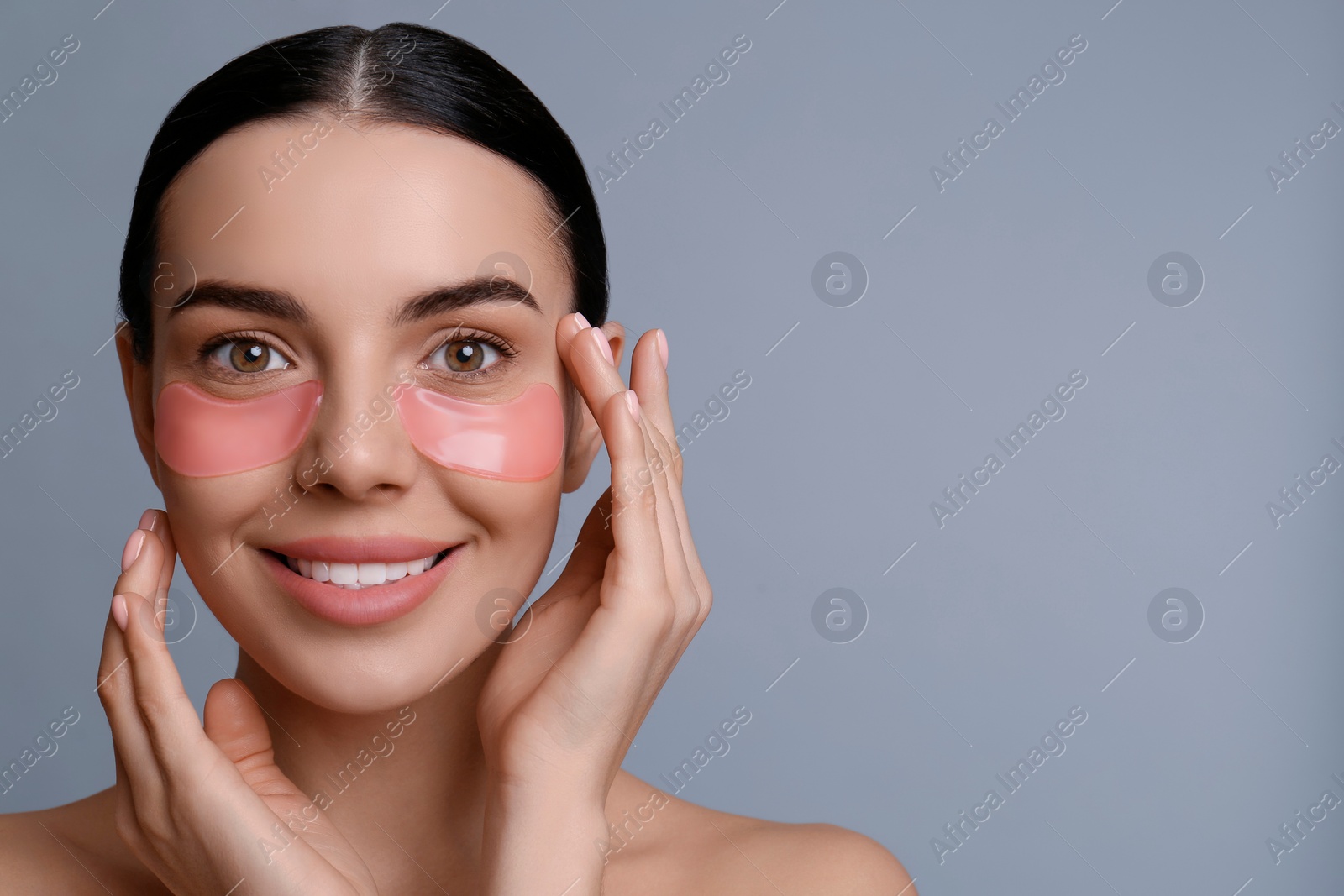 Photo of Beautiful young woman with under eye patches on grey background, space for text