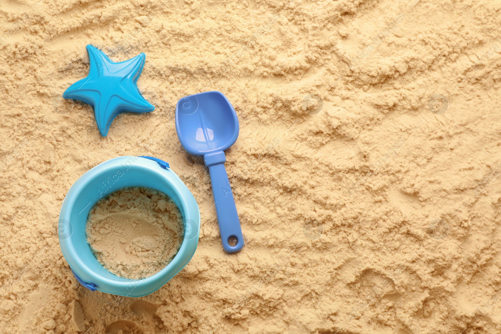 Photo of Flat lay of beach toy kit on sand, space for text. Outdoor play