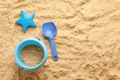 Photo of Flat lay of beach toy kit on sand, space for text. Outdoor play