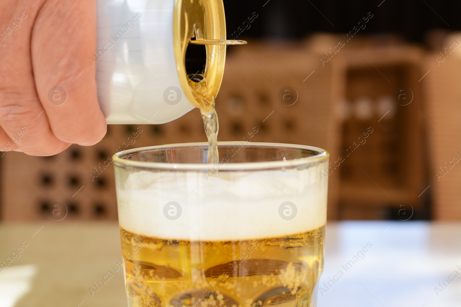 Photo of Man pouring beer from can into glass at table, closeup