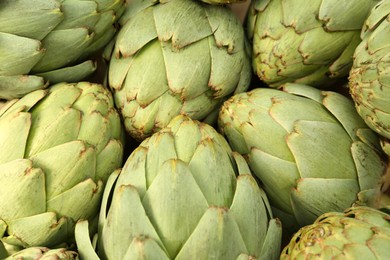 Many fresh raw artichokes as background, top view