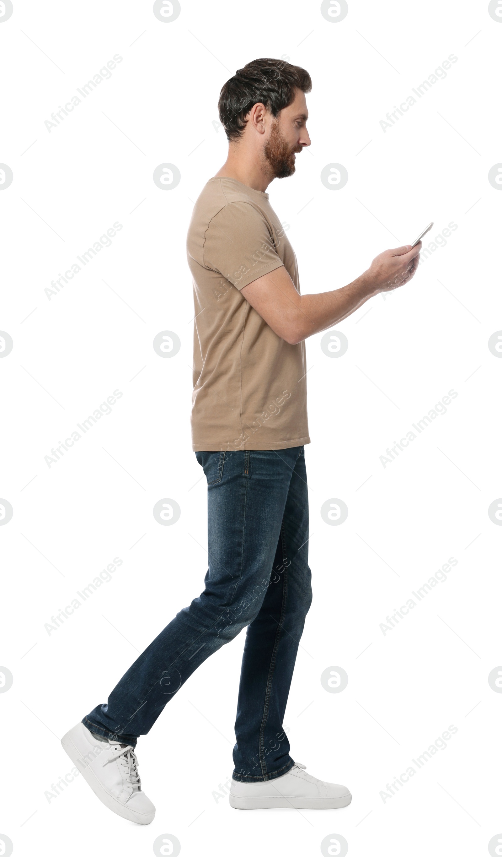 Photo of Handsome man with smartphone walking on white background
