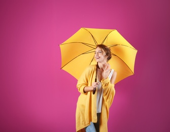 Woman with yellow umbrella on color background. Space for text