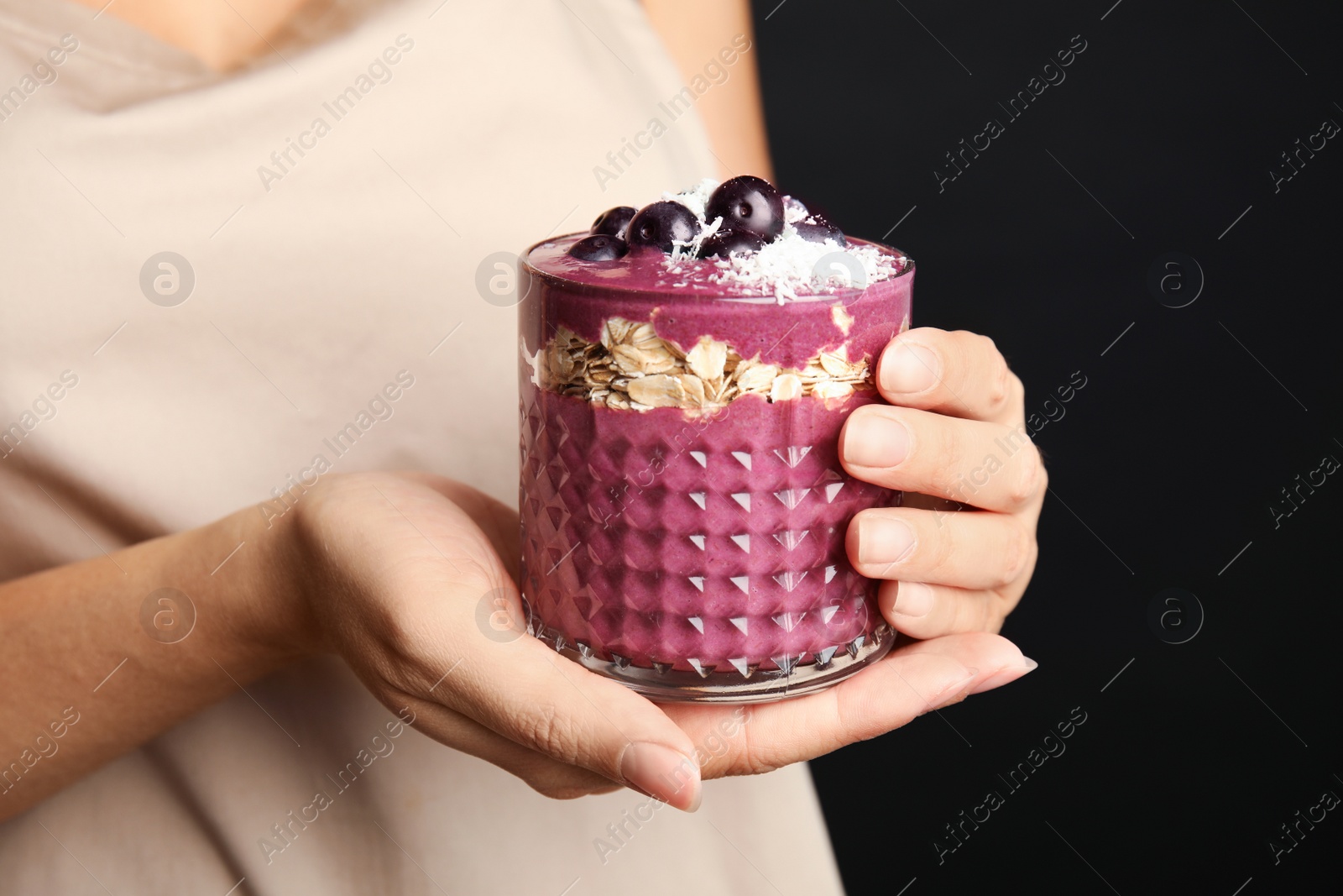 Photo of Woman holding glass with tasty acai smoothie, closeup