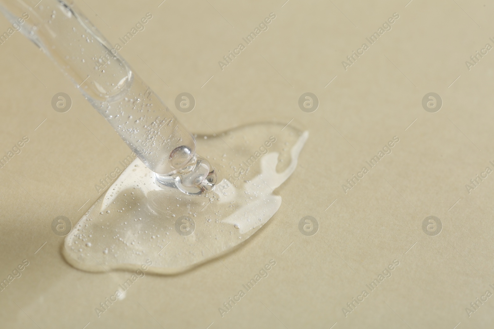 Photo of Pipette with cosmetic serum on beige background, closeup. Space for text