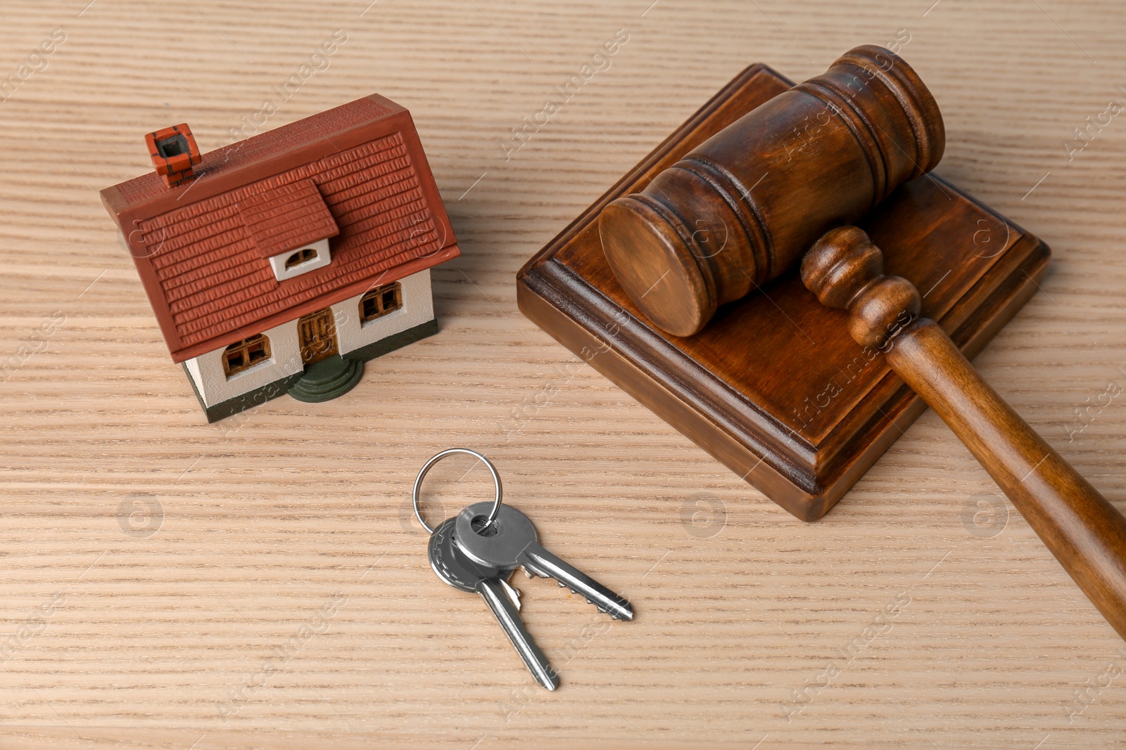 Photo of Judge gavel, keys and house model on wooden background. Estate law concept