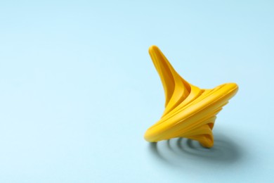 Photo of One yellow spinning top on light blue background, closeup