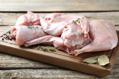 Photo of Fresh raw rabbit meat and spices on wooden table, closeup