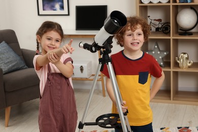 Photo of Cute little children using telescope to look at stars in room