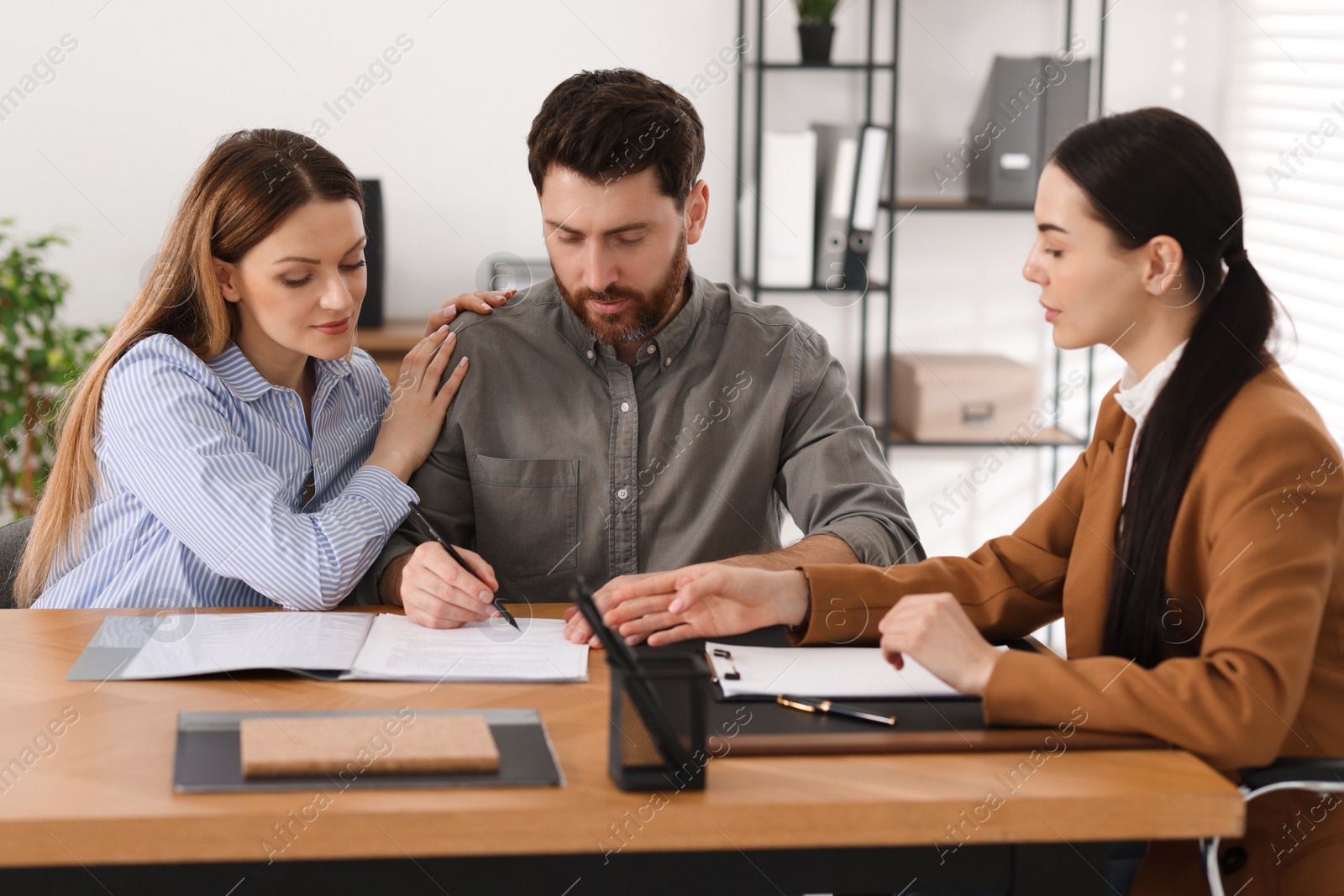 Photo of Couple signing document while having meeting with lawyer in office