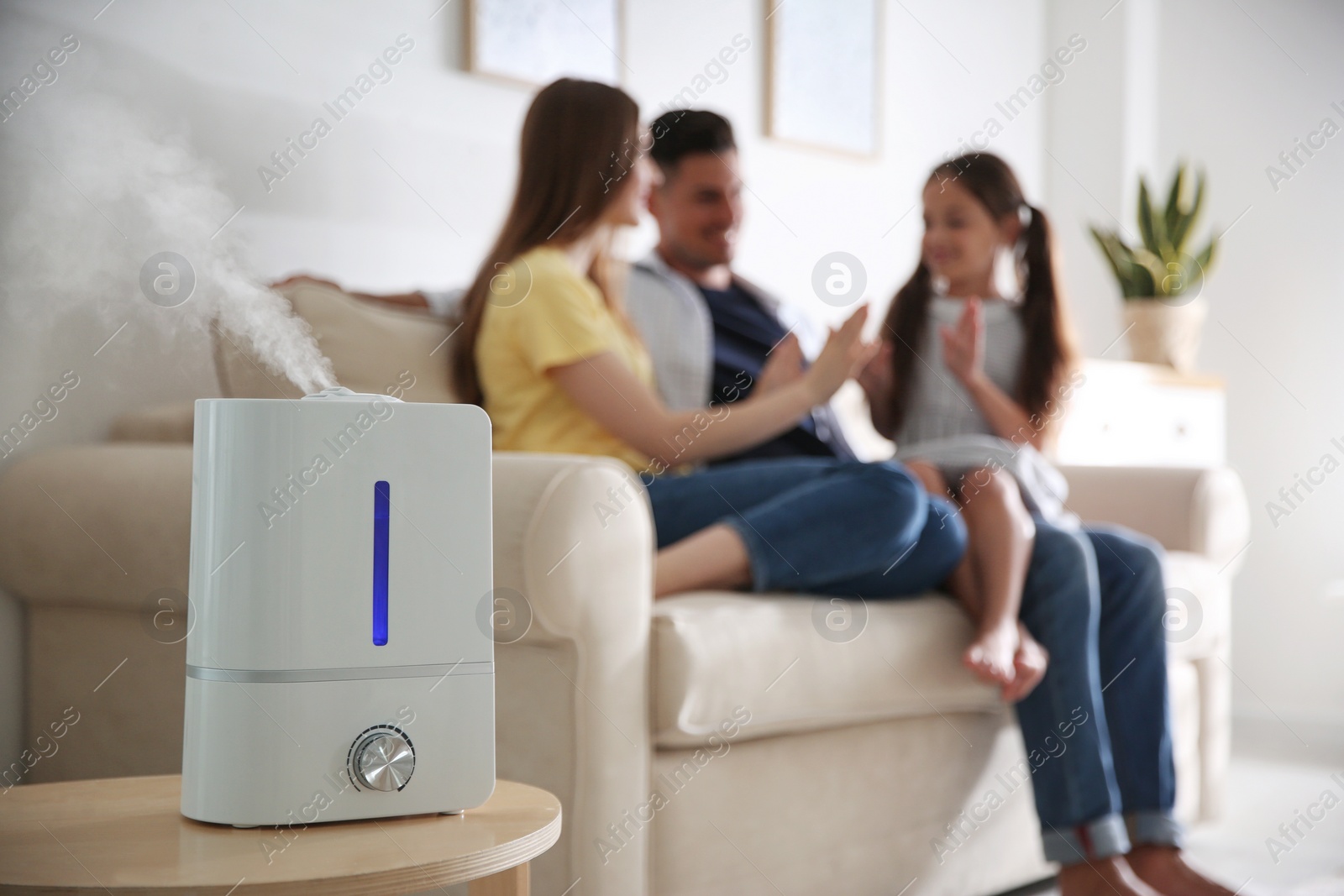 Photo of Modern air humidifier and blurred family on background