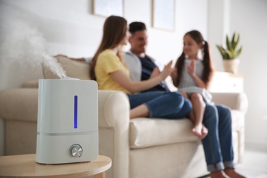 Photo of Modern air humidifier and blurred family on background