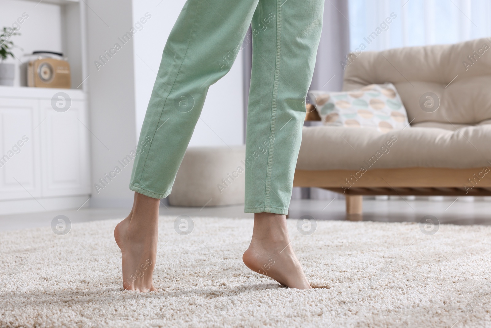 Photo of Woman walking on soft beige carpet at home, closeup