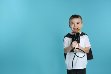 Cute funny boy with microphone on color background. Space for text