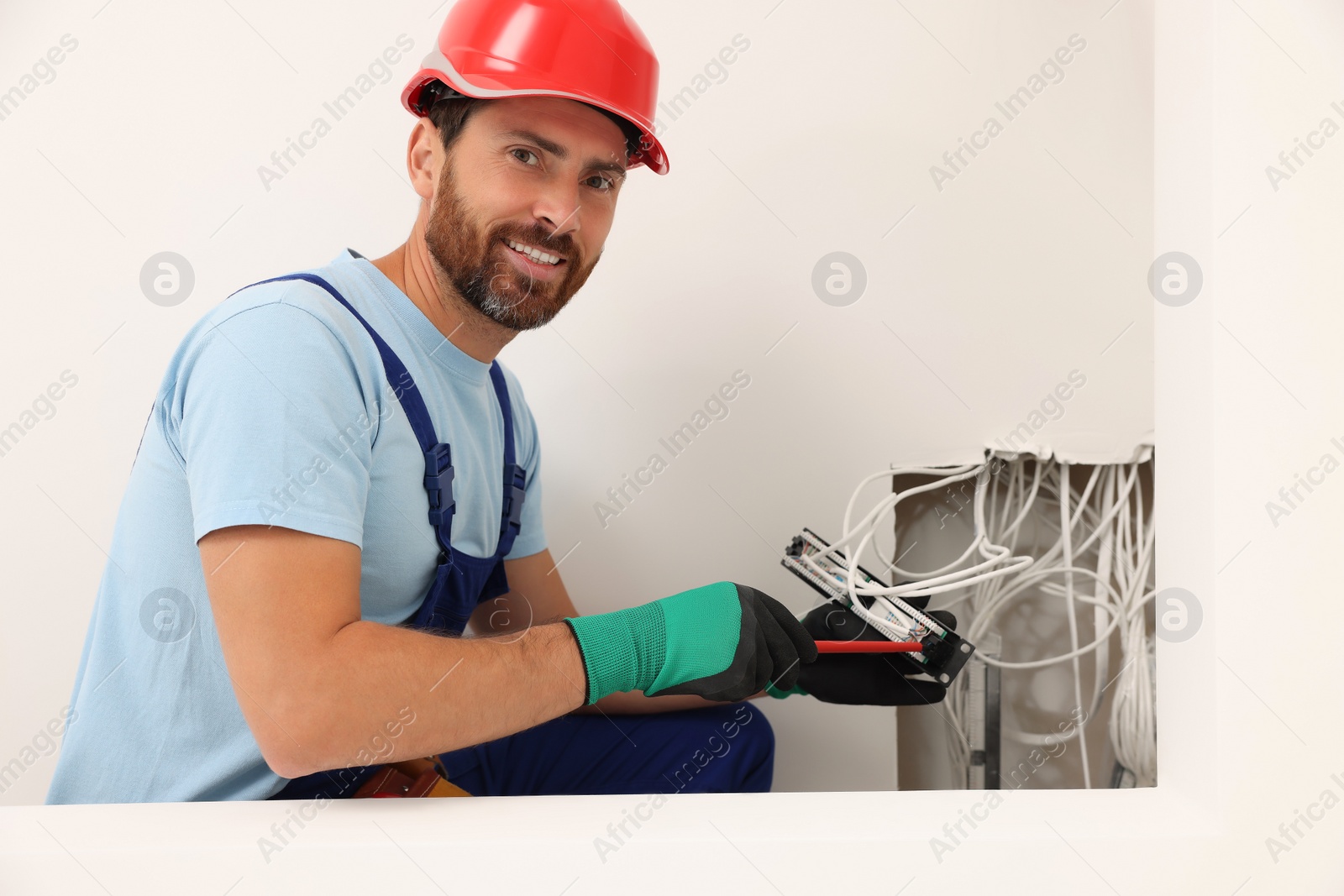 Photo of Electrician with screwdriver fixing patch panel indoors