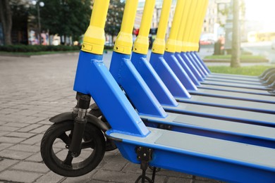 Photo of Many modern electric scooters parked on city street, closeup. Rental service