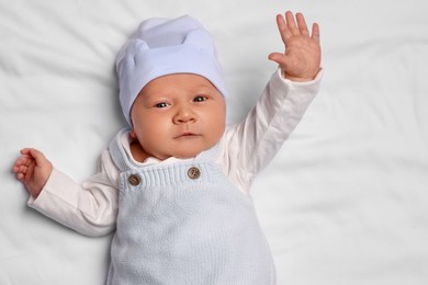 Cute newborn baby lying on white blanket, top view