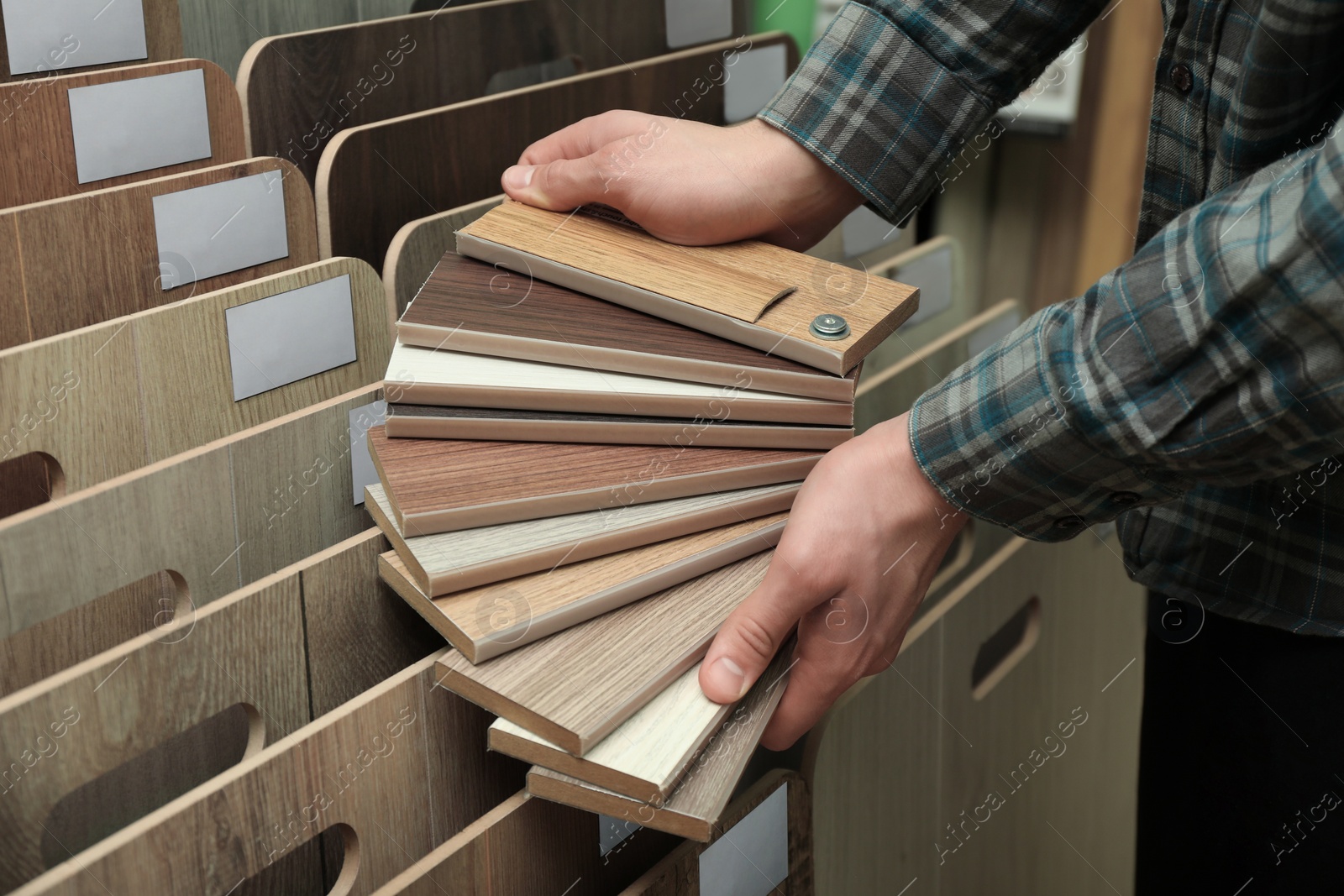 Photo of Man with samples of wooden flooring in shop, closeup