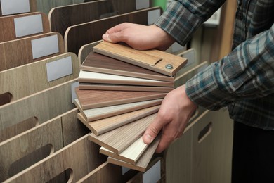 Photo of Man with samples of wooden flooring in shop, closeup