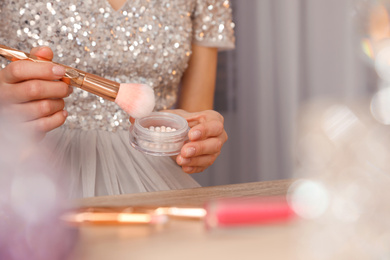 Woman applying makeup at dressing table, closeup