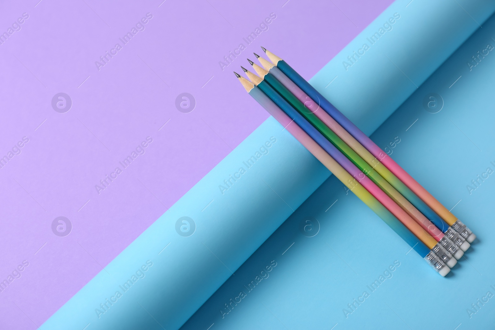 Photo of Pencils and rolled paper on color background. Space for text