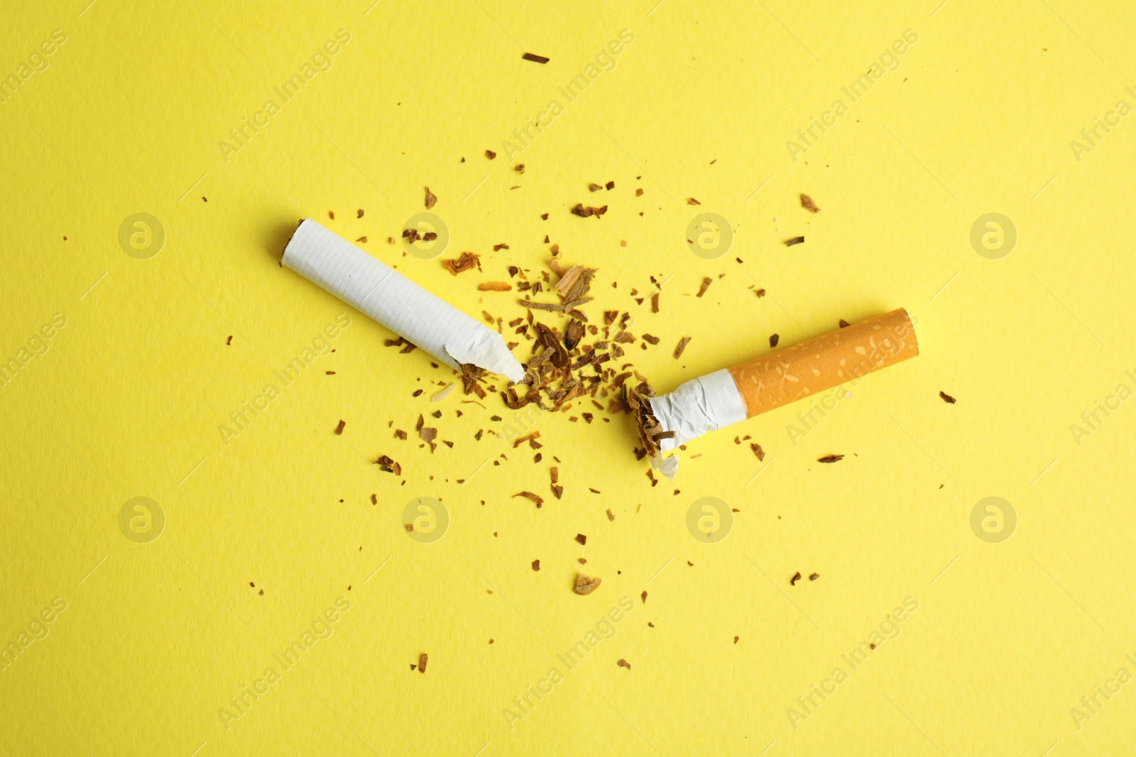 Photo of Broken cigarette on yellow background, flat lay. Quitting smoking concept