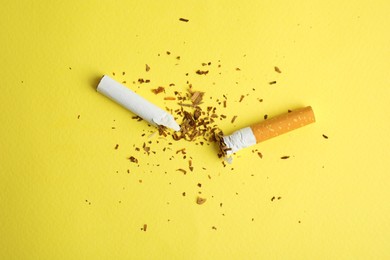 Broken cigarette on yellow background, flat lay. Quitting smoking concept