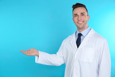 Photo of Male dentist holding something on color background