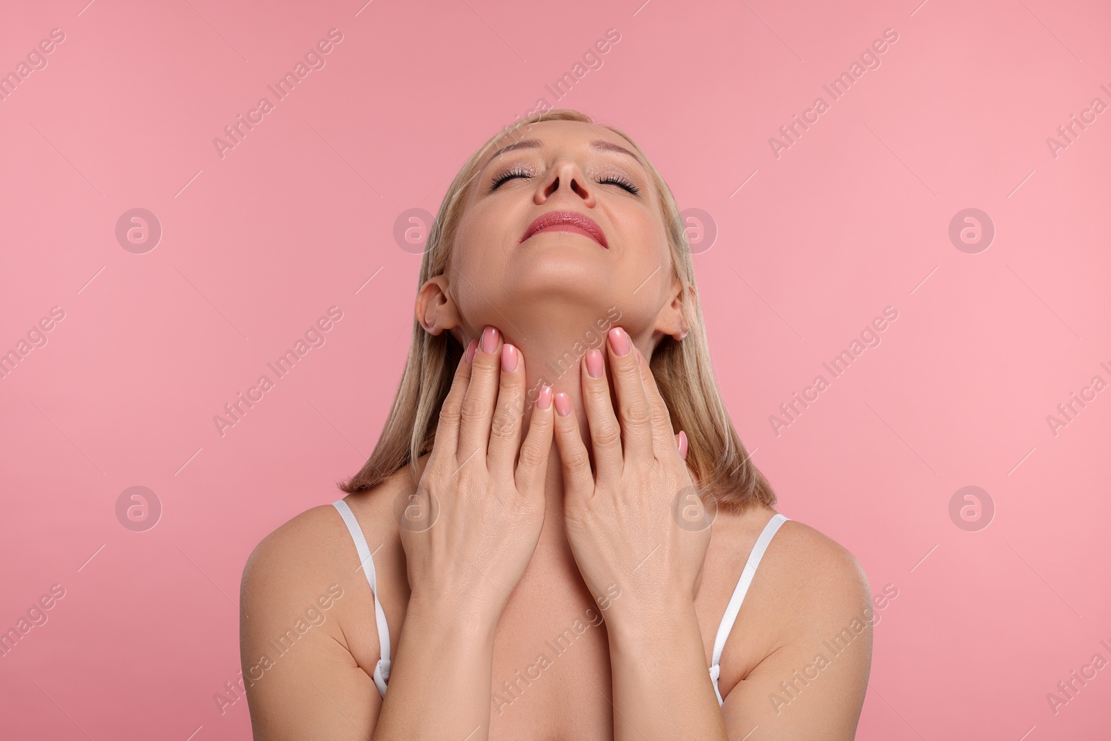 Photo of Beautiful woman touching her neck on pink background