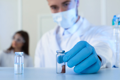 Photo of Scientist taking medical ampoule indoors, focus on hand. Laboratory analysis