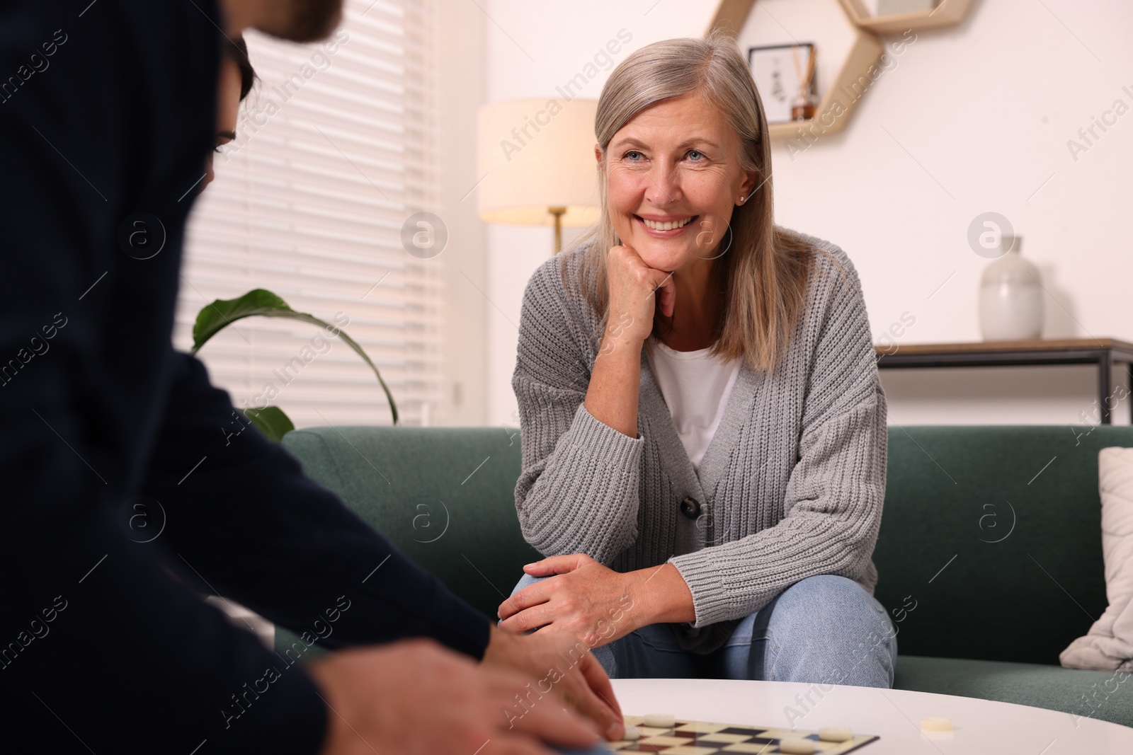 Photo of Smiling senior woman playing checkers at home