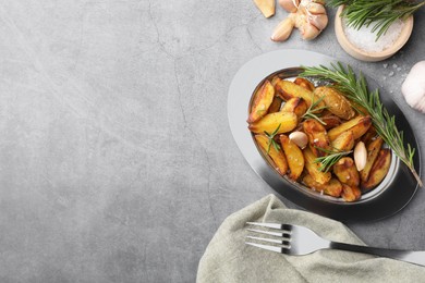 Tasty baked potato and aromatic rosemary served on grey textured table, flat lay. Space for text