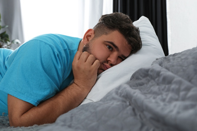 Photo of Overweight man suffering from depression on bed