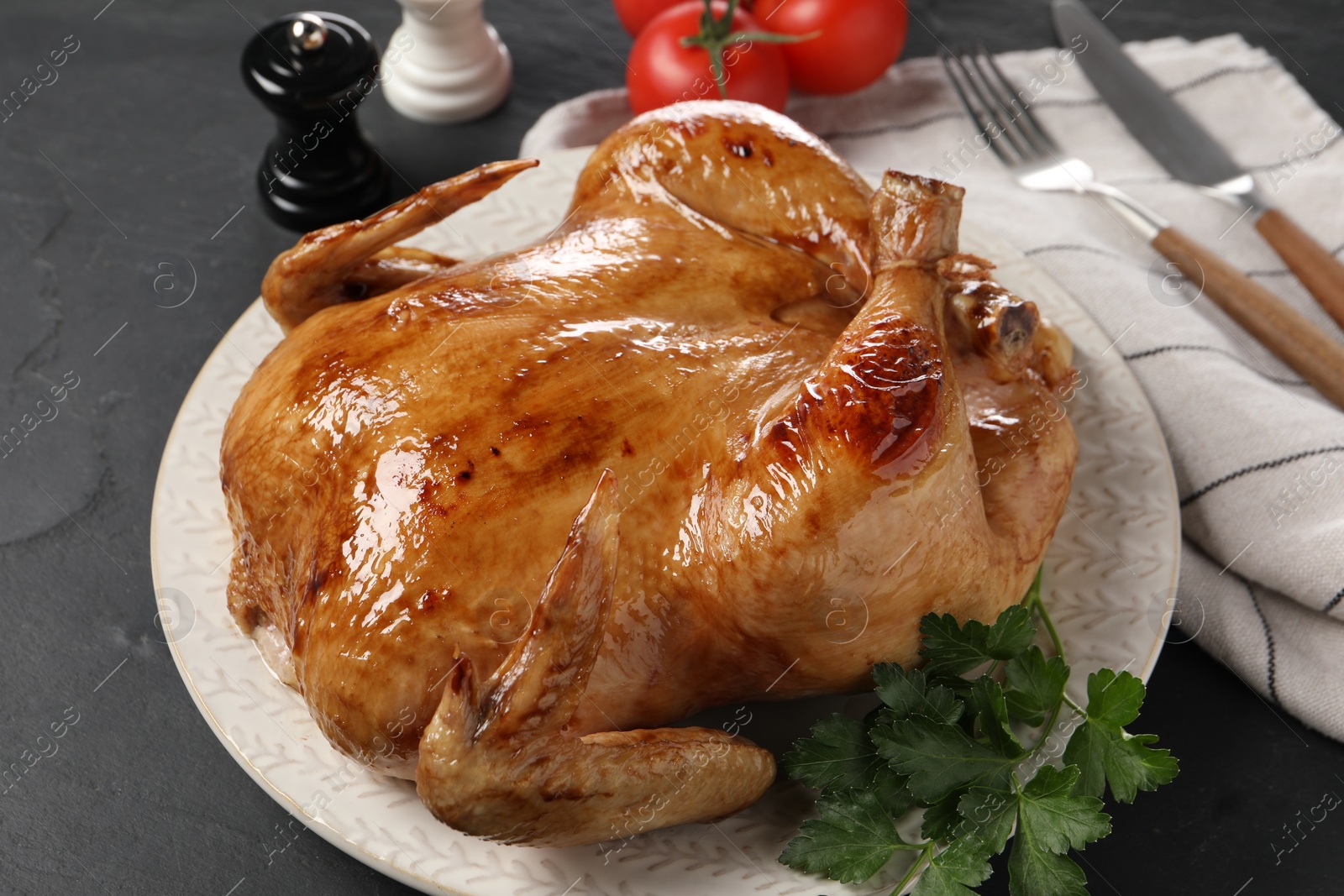 Photo of Tasty roasted chicken with parsley served on grey textured table