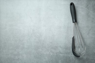 Photo of Metal whisk on gray table, top view. Space for text