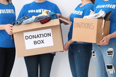 Team of volunteers with donation boxes on light background