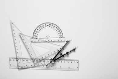 Photo of Different rulers and compass on white background, top view