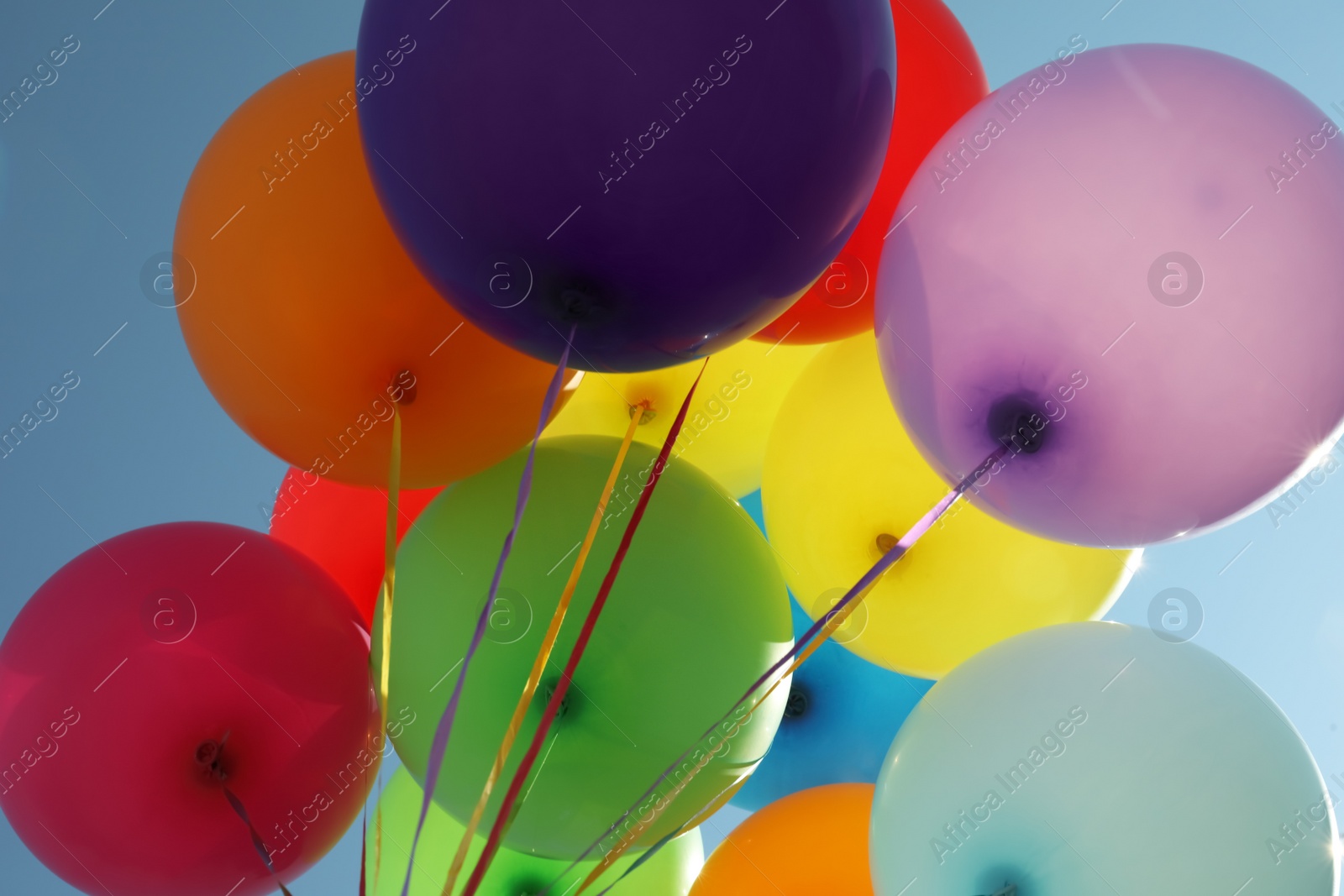 Photo of Bunch of colorful balloons against blue sky, low angle view