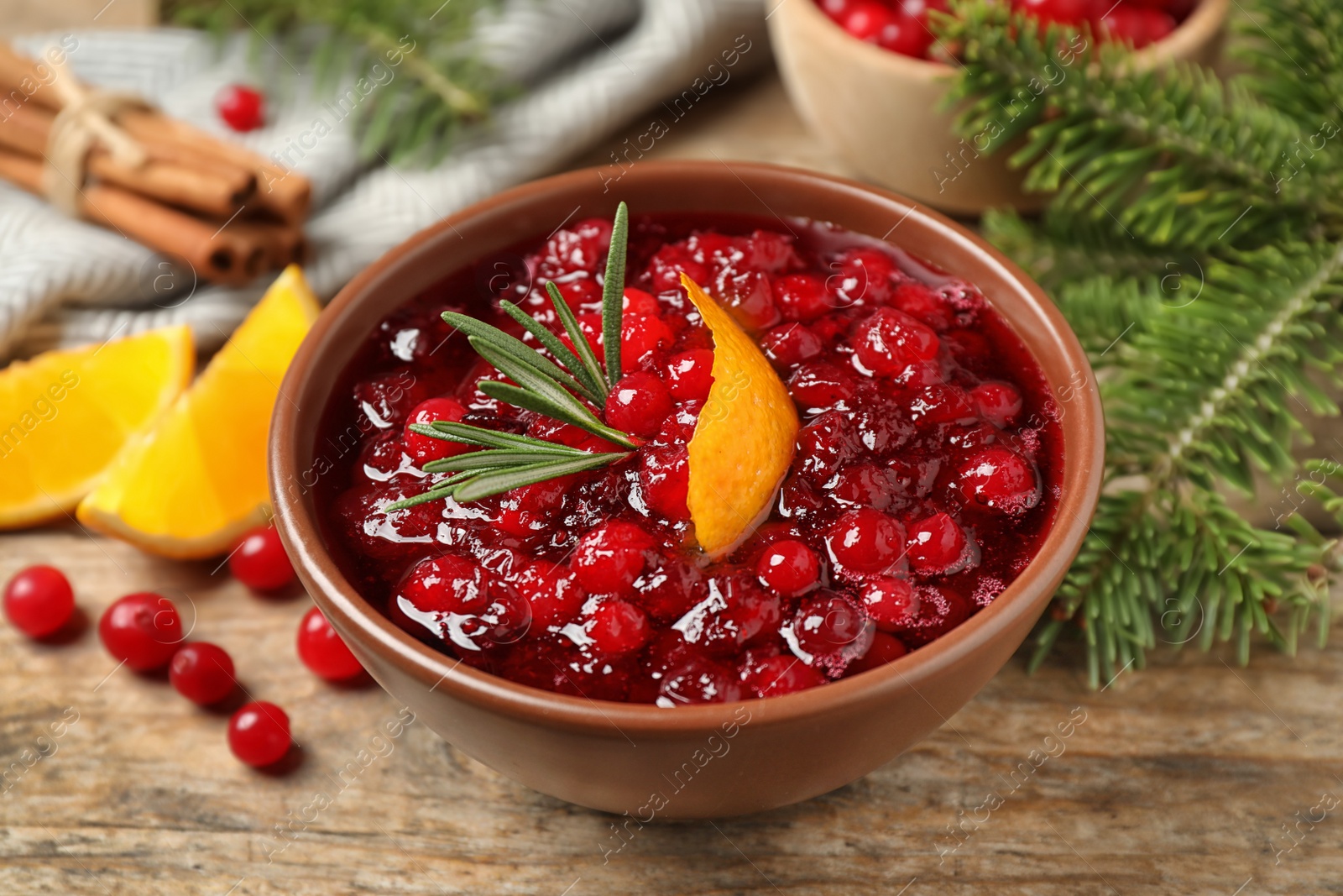 Photo of Cranberry sauce with orange peel and rosemary on wooden table