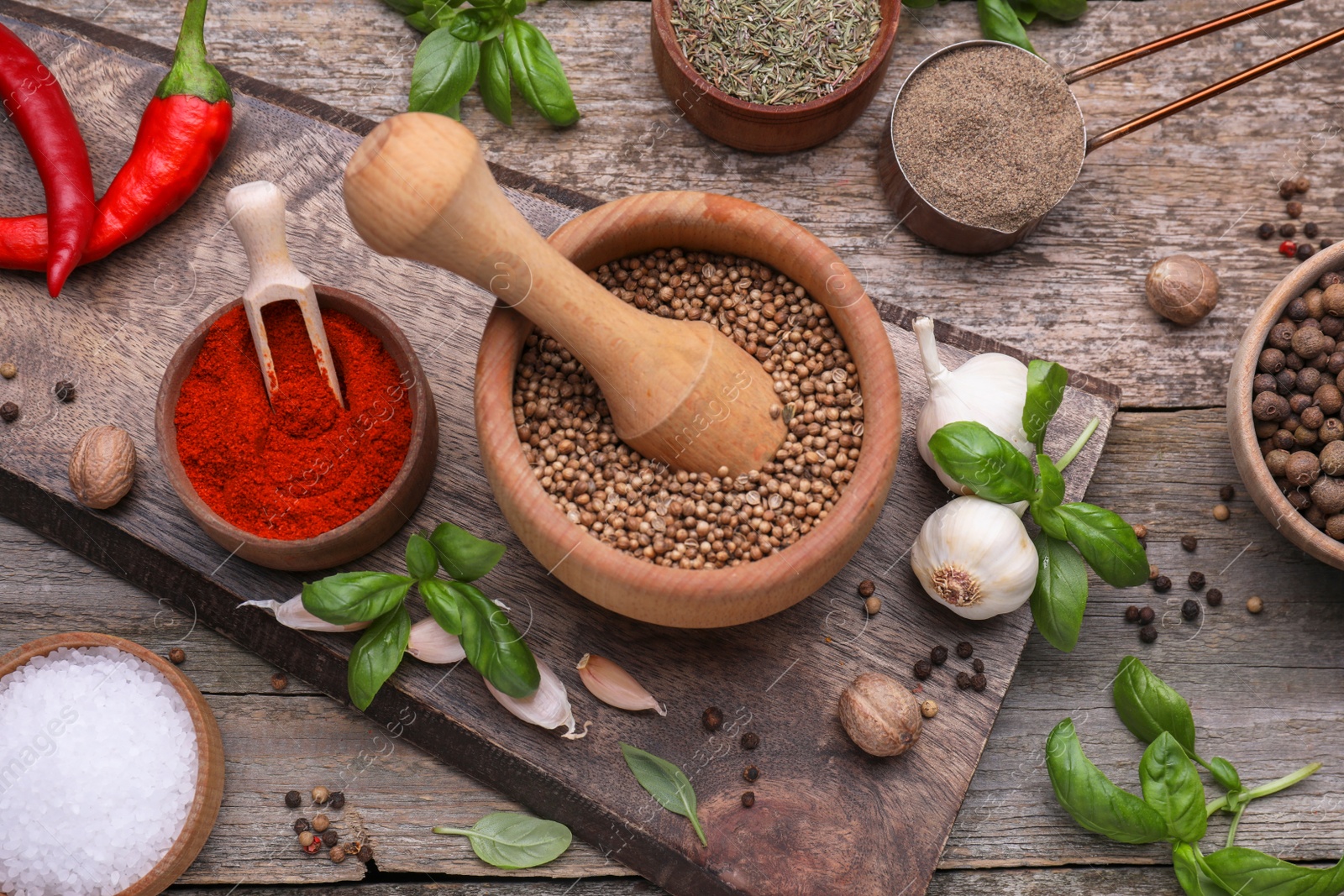 Photo of Mortar with pestle and different spices on wooden table, above view