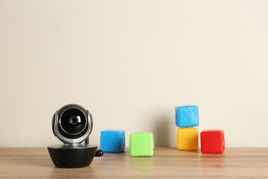 Photo of Baby monitor and toys on wooden table. CCTV equipment