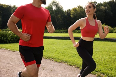 Healthy lifestyle. Couple running in park on sunny day, closeup