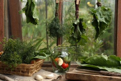 Bunches of fresh green herbs over table with ingredients indoors