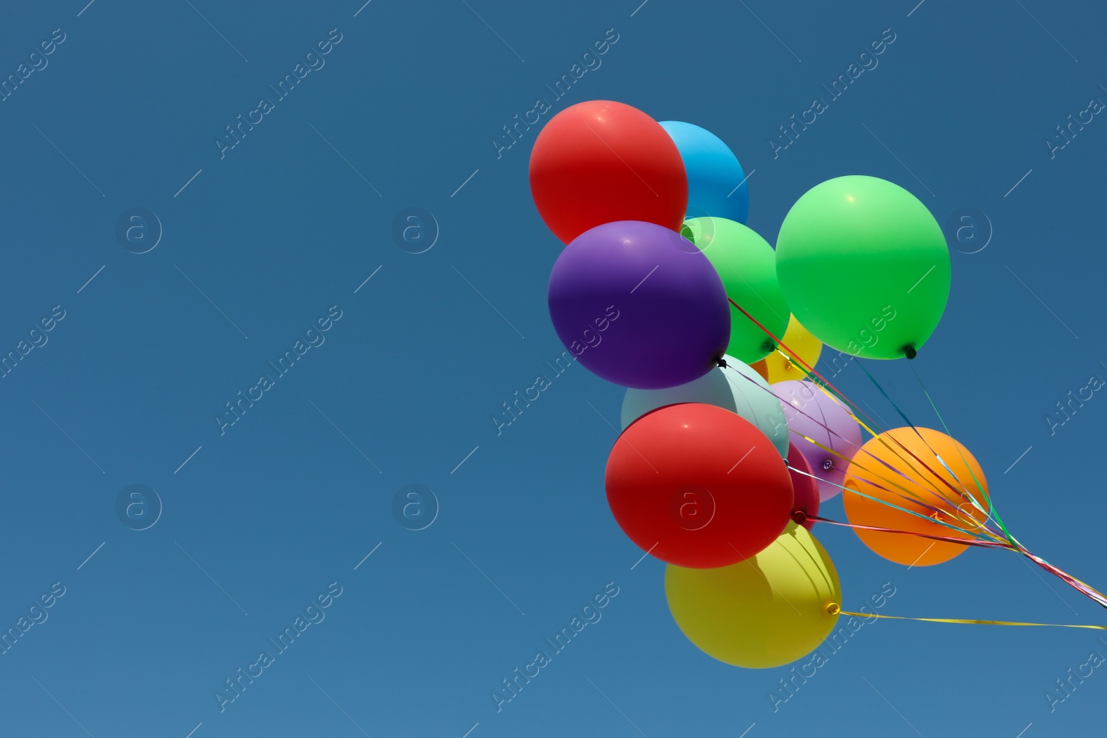 Photo of Bunch of colorful balloons against blue sky. Space for text