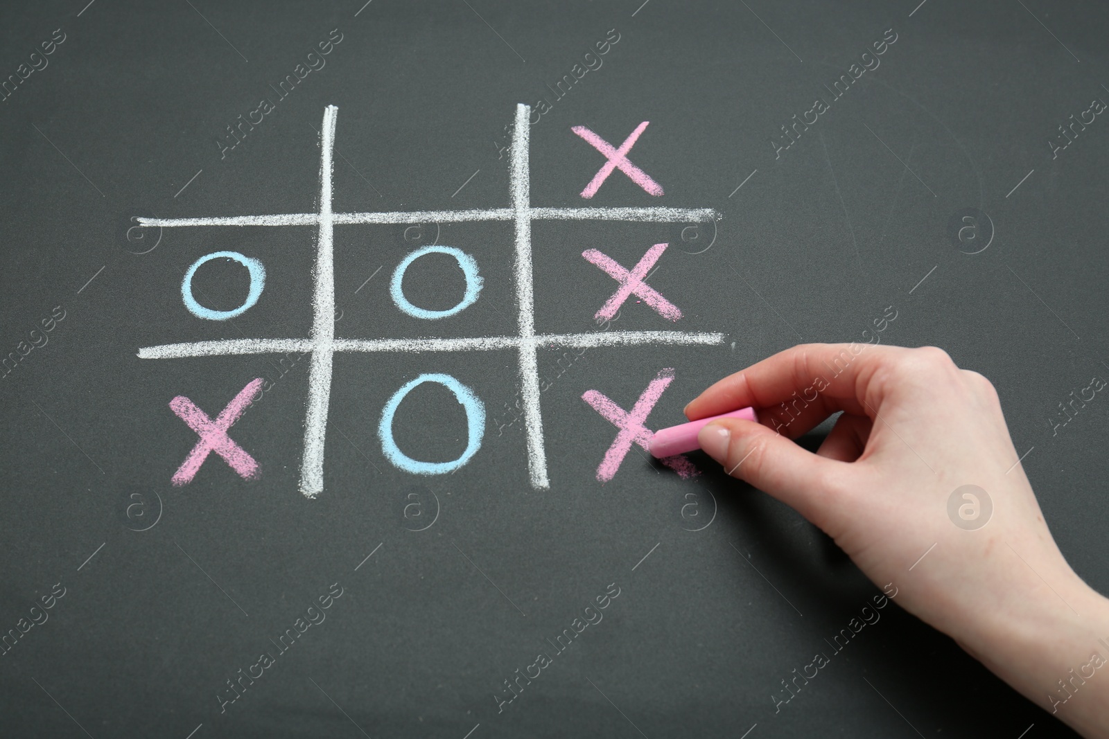 Photo of Woman playing tic tac toe on chalkboard, closeup